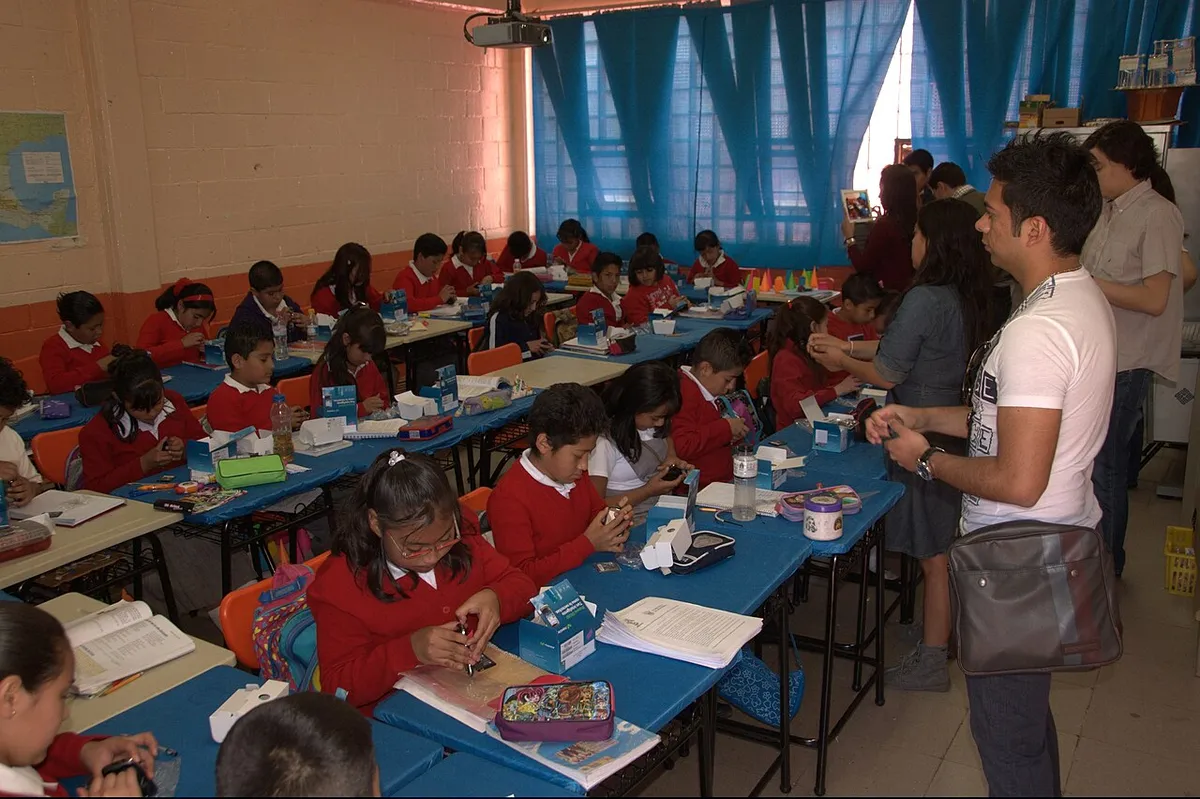 Alumnas y alumnos de primaria trabajando en sus mesas dentro del salón de clases