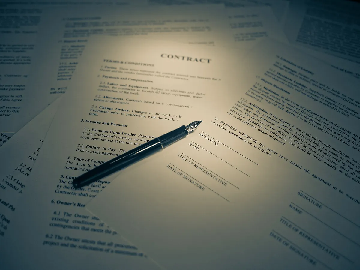 Pessoa assinando um contrato com caneta, no momento de formalizar um financiamento