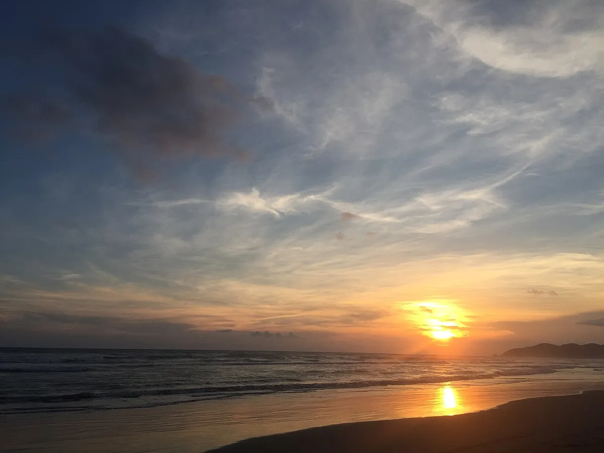 Pôr do sol em praia de águas claras — no Brasil, a virada de ano cai em pleno verão e é tradição passá-la na praia