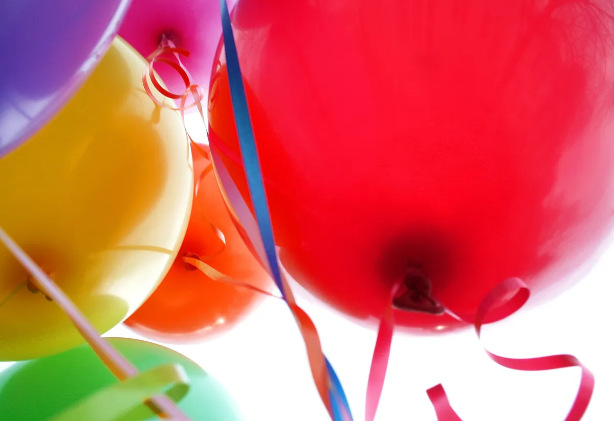 Balões coloridos de festa de aniversário vistos de baixo, com fitas