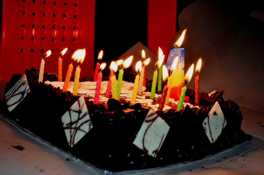 Bolo de chocolate de aniversário com muitas velinhas coloridas acesas