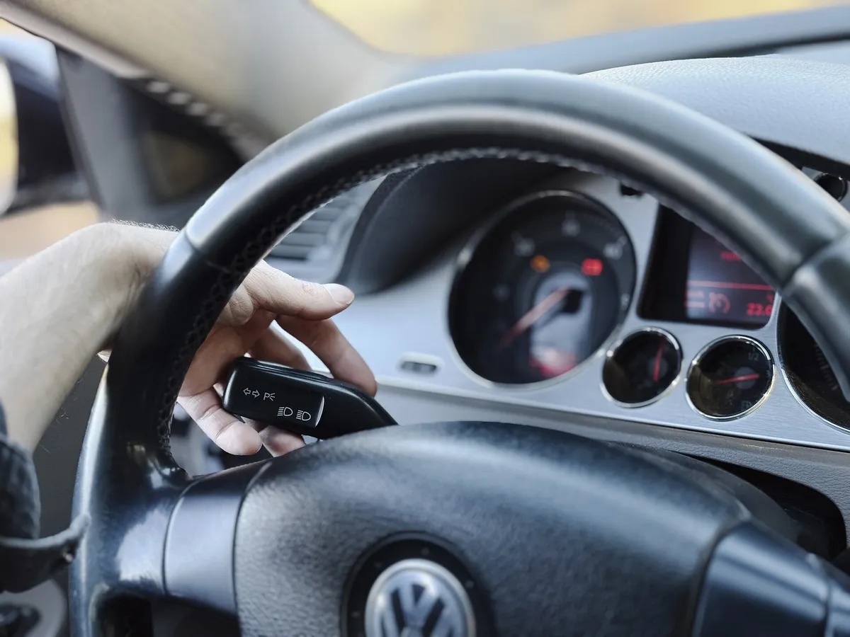 Mão segurando a chave do carro junto ao volante, prestes a ligar o veículo financiado