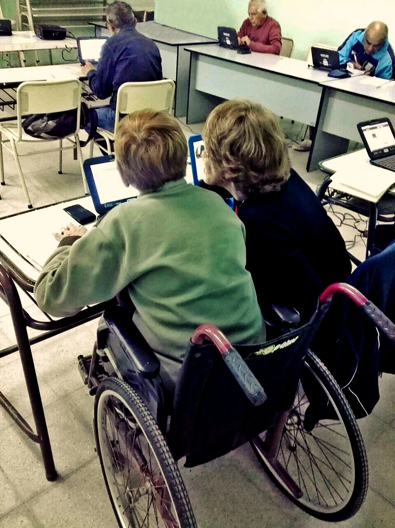 Una mujer usuaria de silla de ruedas trabajando en una computadora portátil durante una clase