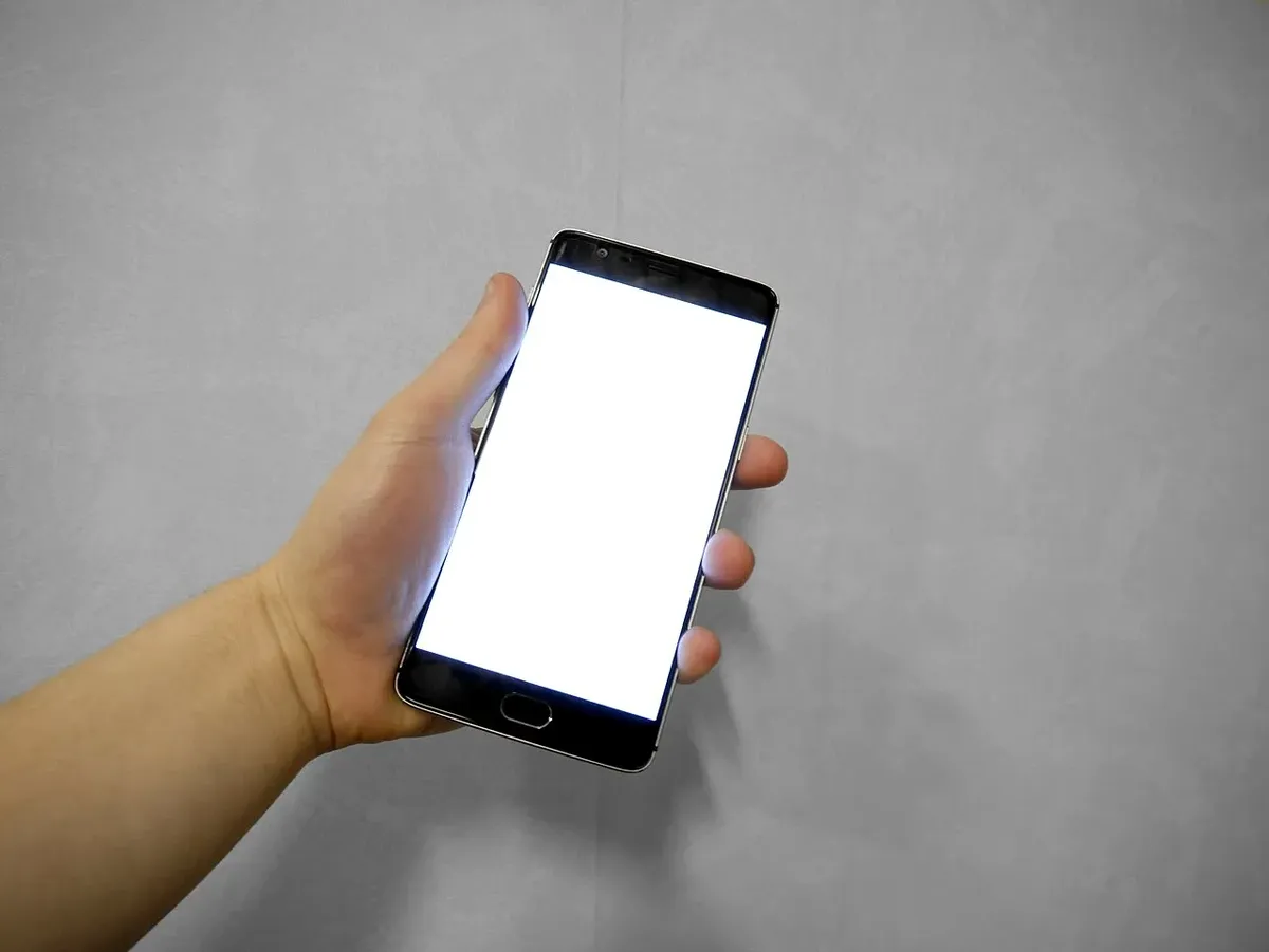 Mano sosteniendo un teléfono inteligente con la pantalla encendida