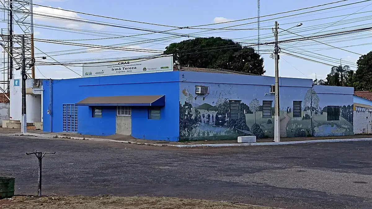Fachada azul de um CRAS (Centro de Referência de Assistência Social) em Aragoiânia, Goiás, com placa de identificação do serviço