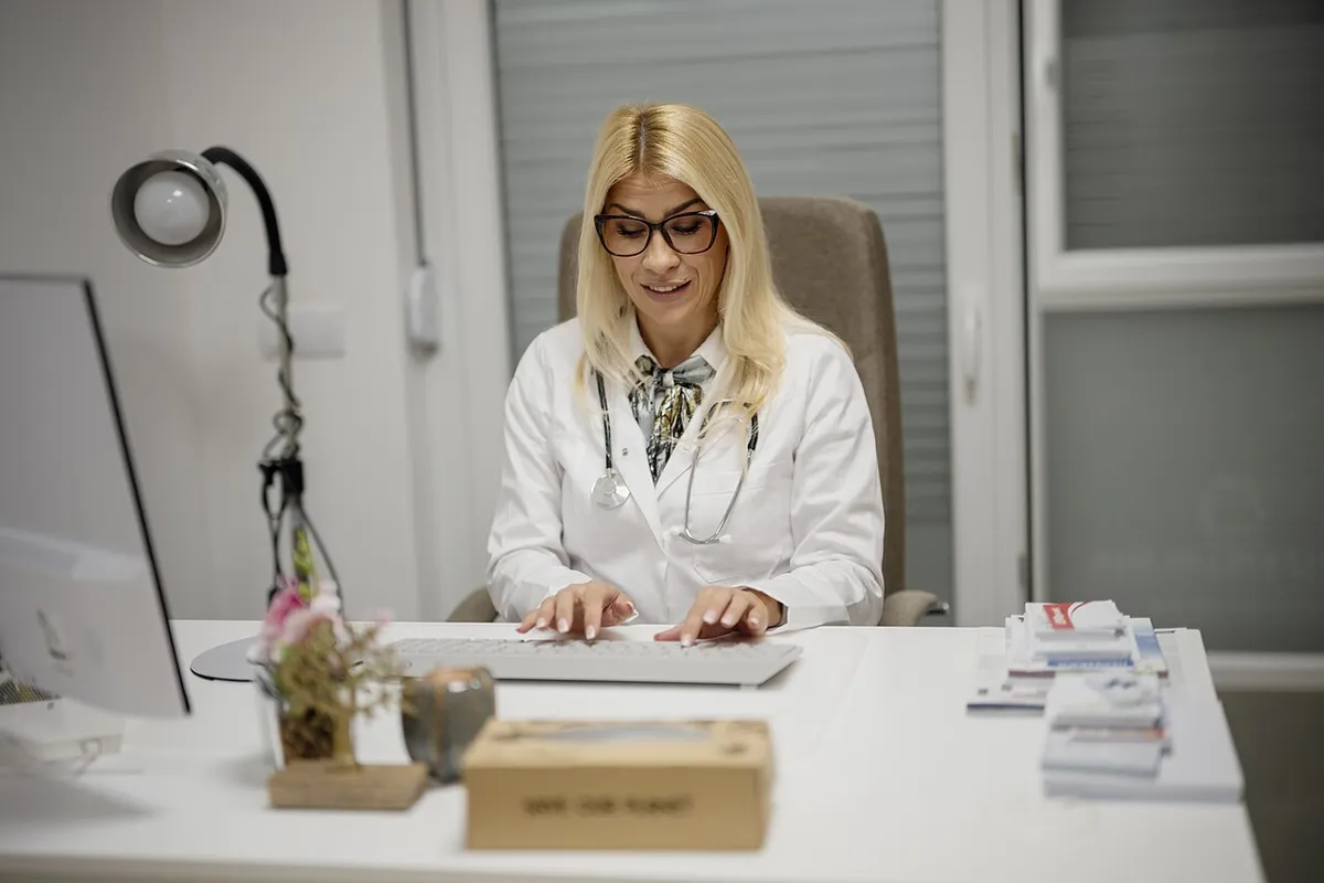 Doctora trabajando en su consultorio, frente a su computadora