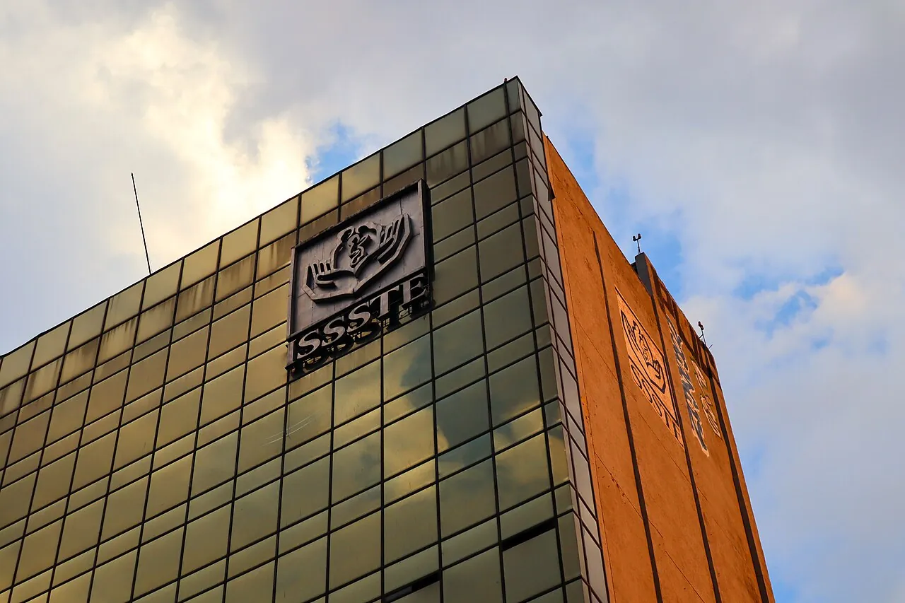 Esquina superior de un edificio de cristal dorado con el logotipo del ISSSTE en la fachada
