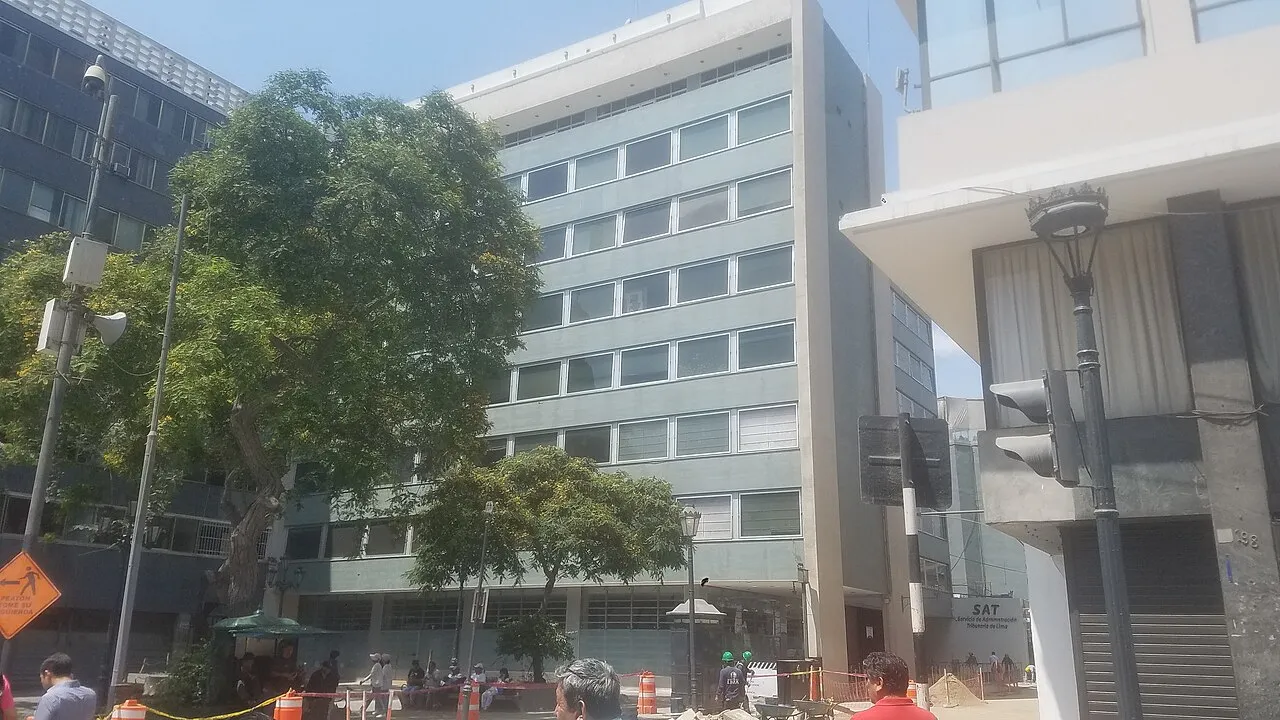 Edificio moderno de oficinas del SAT con cristales, visto desde la calle en un día soleado