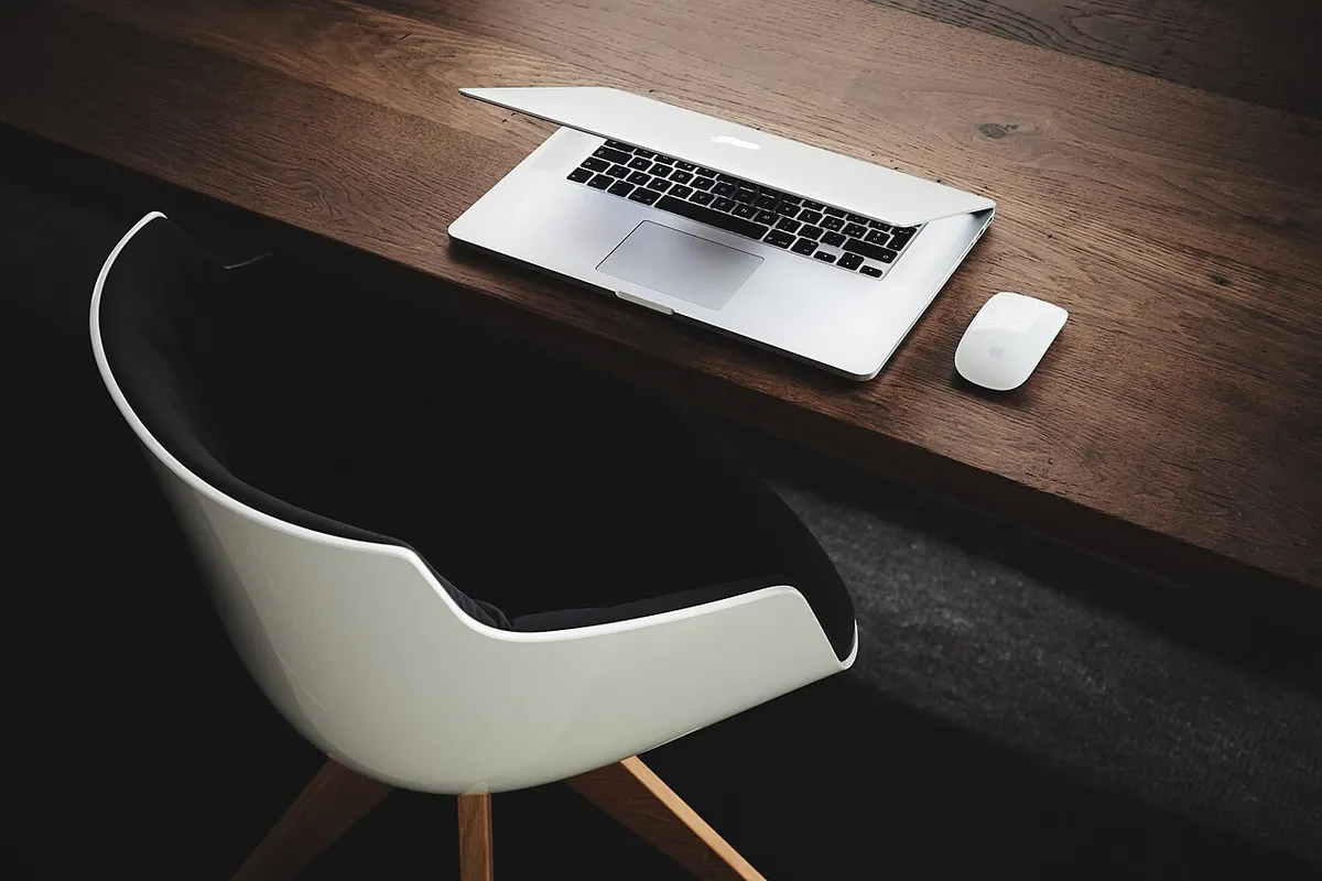 An empty office desk with a monitor and chair after the workday has ended