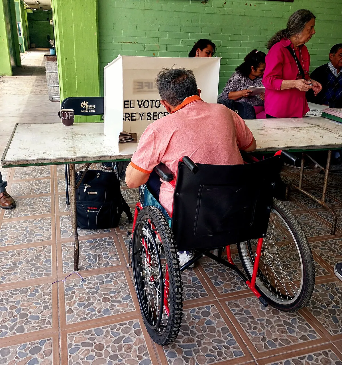 Un hombre usuario de silla de ruedas emitiendo su voto en una casilla durante una elección federal en México