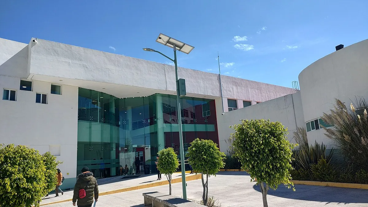 Fachada moderna de un hospital del IMSS-Bienestar con ventanales y explanada de acceso