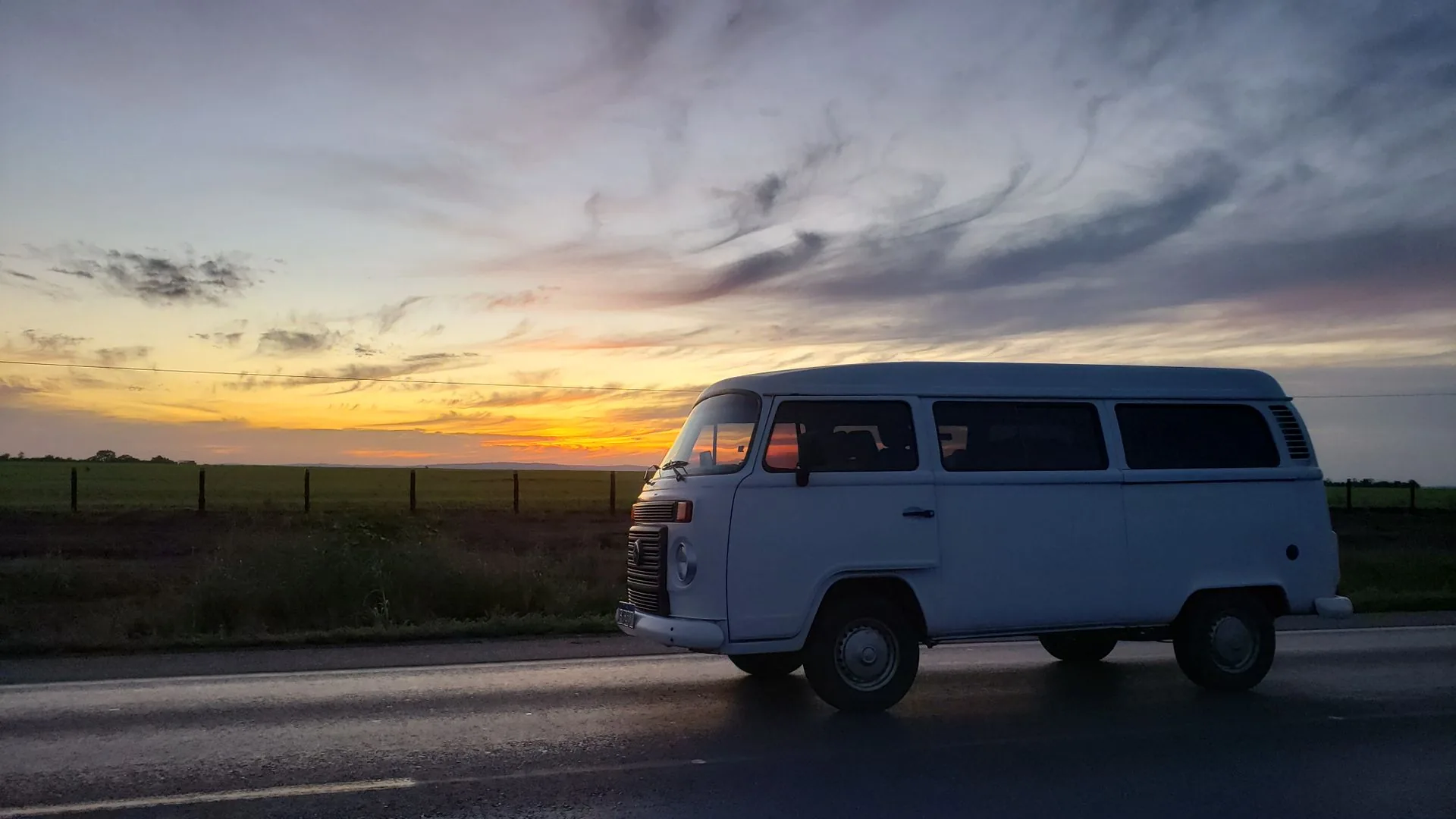 Kombi em uma estrada de Mato Grosso ao pôr do sol, pronta para a viagem do fim de semana