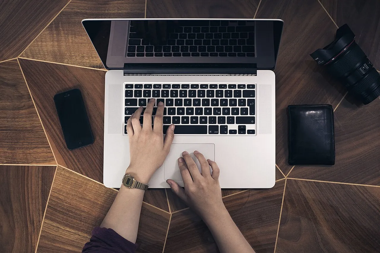 Manos escribiendo en el teclado de una laptop durante una consulta en línea