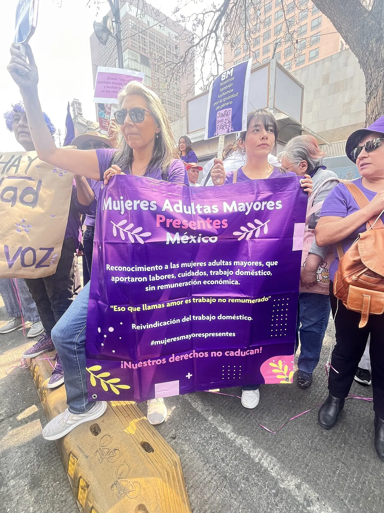 Mujeres adultas mayores sosteniendo una manta que pide reconocer el trabajo doméstico y de cuidados no remunerado