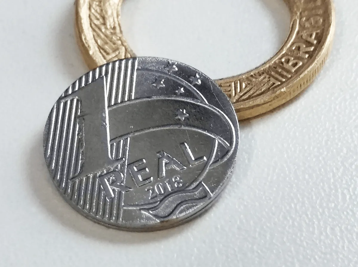 Moeda de um real brasileiro em destaque, com o valor de face e o desenho da efígie da República