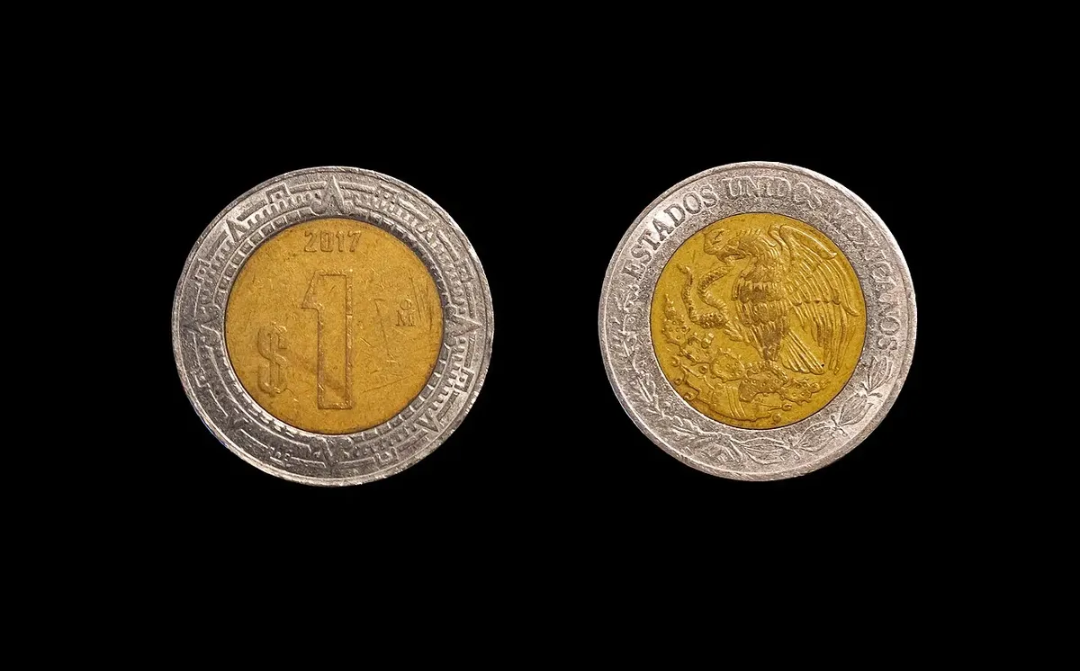 Moneda mexicana de un peso vista por el anverso y el reverso sobre fondo negro