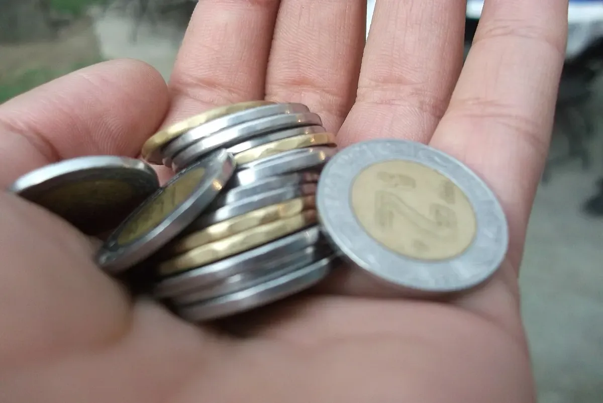 Monedas mexicanas actuales sostenidas en la palma de una mano