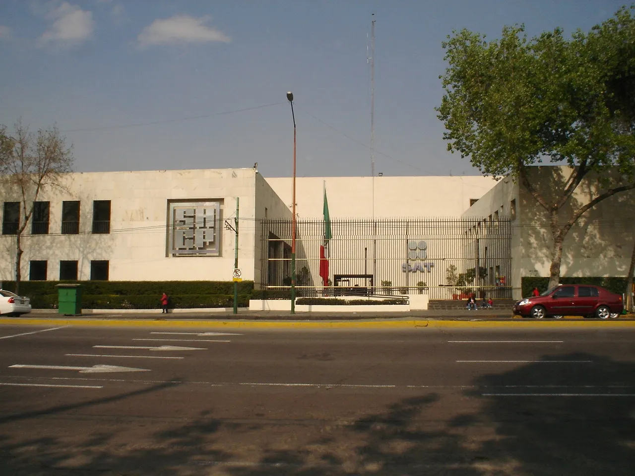Fachada blanca de las oficinas centrales del Servicio de Administración Tributaria en la Ciudad de México, con la bandera de México al frente