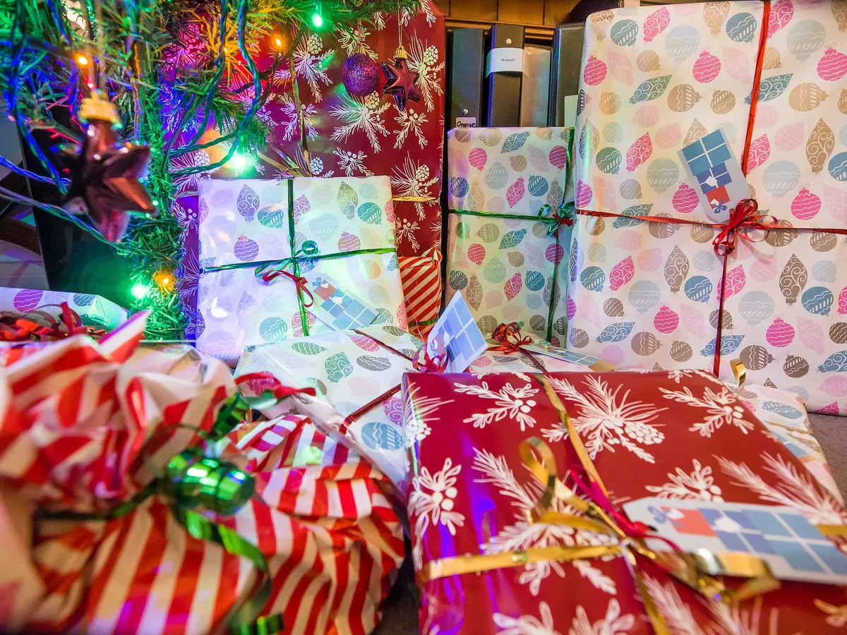 Presentes embrulhados em papéis coloridos reunidos sob a árvore de Natal iluminada