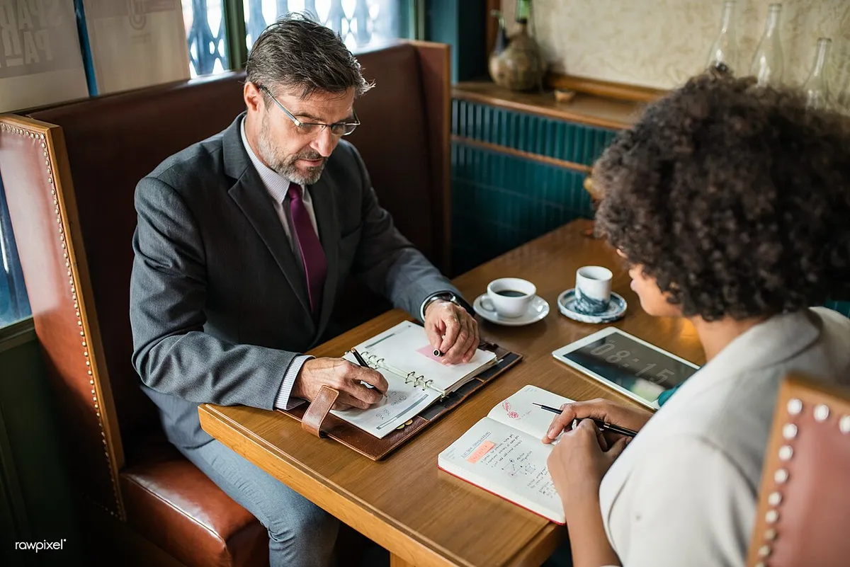 Dos personas revisando documentos en una mesa de trabajo
