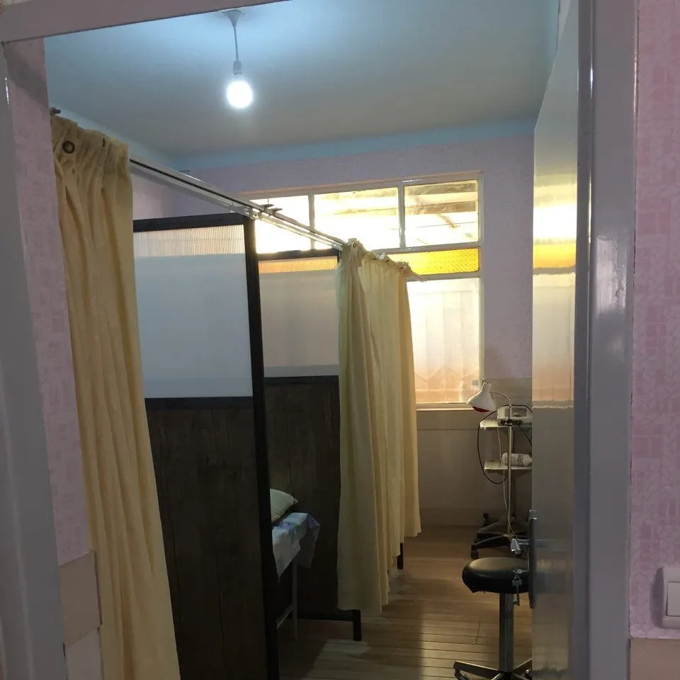 Sala de terapia física com equipamentos de reabilitação, incluindo barras paralelas e maca de atendimento