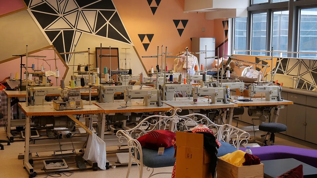 Un taller de costura moderno con máquinas de coser alineadas en mesas de trabajo